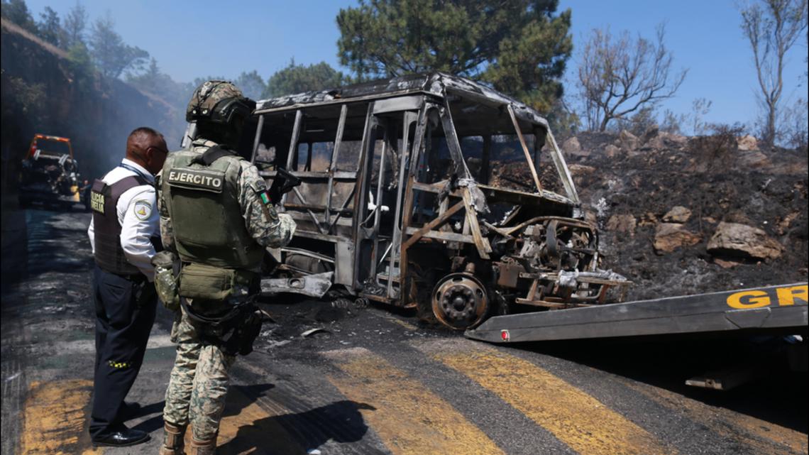 A soldier stands guard by a charred vehicle that was set on fire in Cointzio, Mexico, Sunday, Feb. 22, 2026.