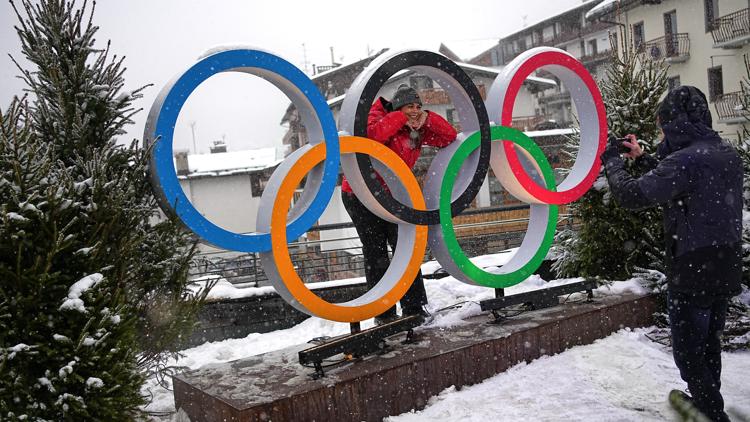 A woman poses for a photo with the Olympic rings ahead of the 2026 Winter Games in Cortina d'Ampezzo, Italy, Feb. 4, 2026.