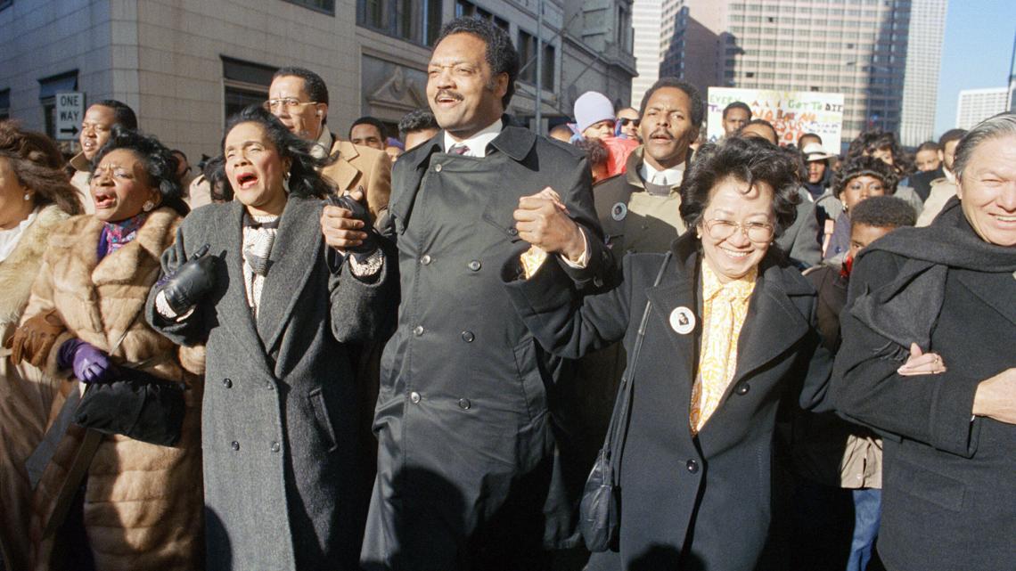 Coretta Scott King holds hands with the Rev. Jesse Jackson and Christine Farris, sister of Martin Luther King, Jr., Jan. 19, 1987.