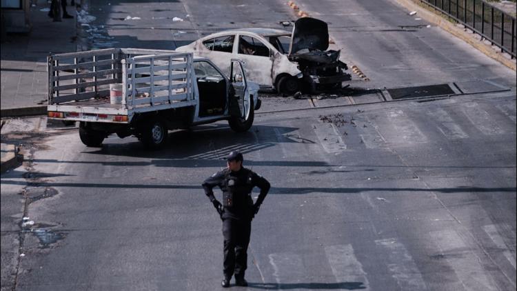 A police officer stands guard by a charred vehicle after it was set on fire on a road in Guadalajara, Jalisco state, Mexico, on Feb. 22, 2026.