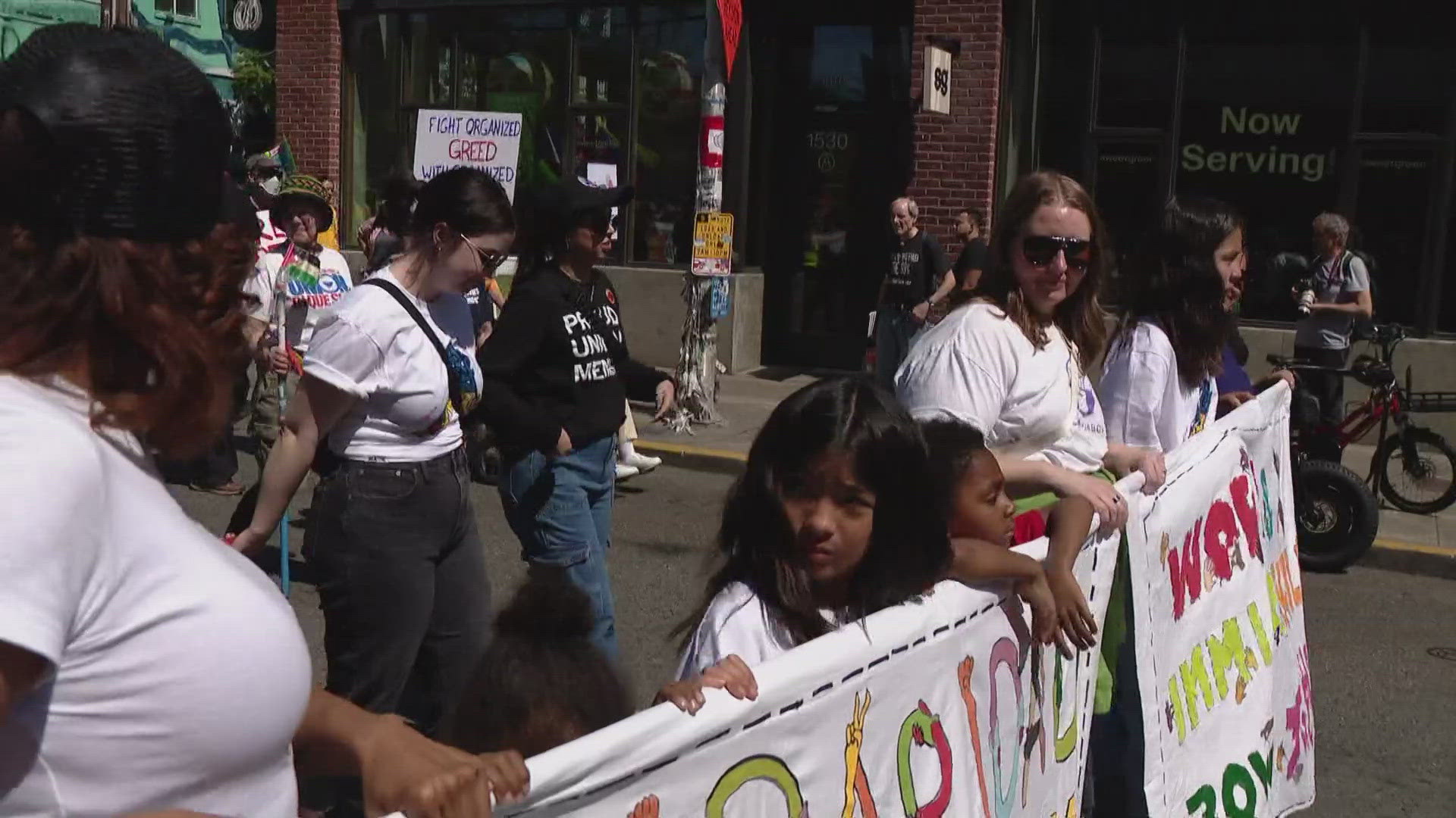 Protesters chanted and waved signs beneath this year’s event slogan: “We Make America Work.”