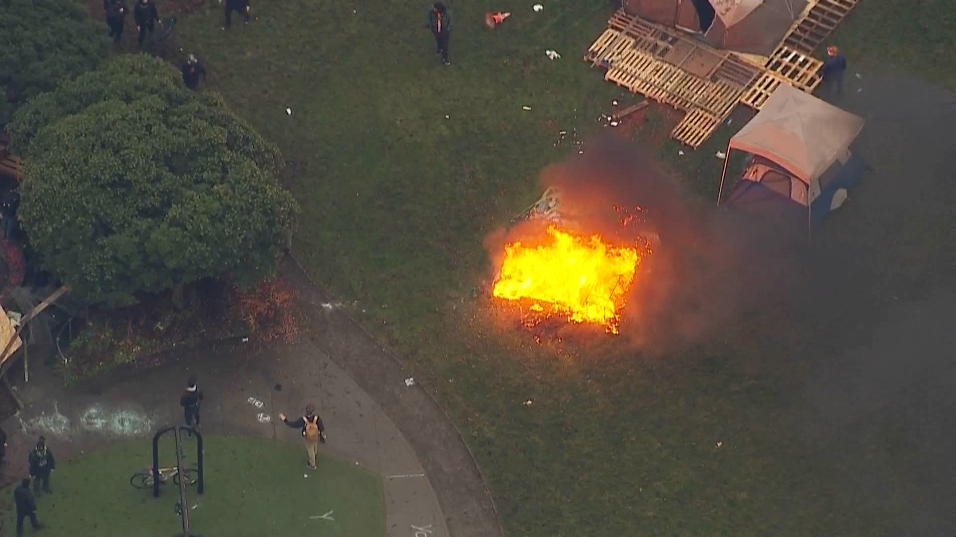 Protesters set a fire while resisting the cleanout of a homeless encampment at Cal Anderson Park