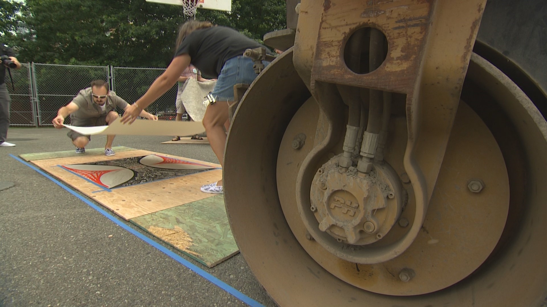 Teams of artists use heavy steamrollers to press colorful art prints.
